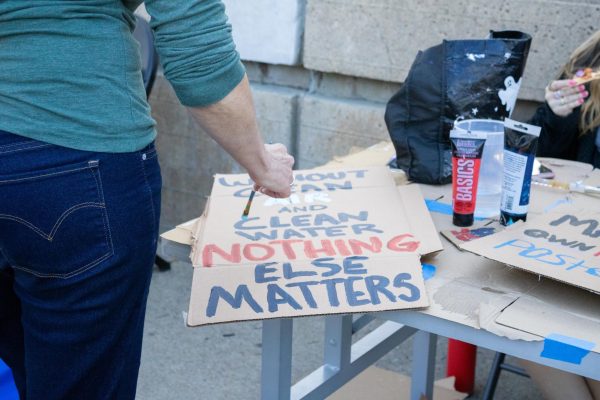 A member of the Environmental Justice Club paints a sign. 